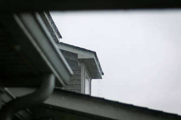 A close view of a rain gutter along a roof edge against a blue sky.