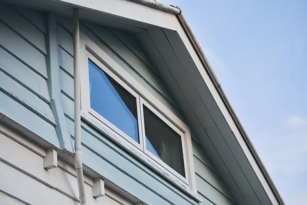 Clean exterior windows on a house gable with blue sky behind.